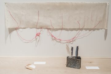 <p>Cecilia Vicuña (Chile, born 1948). <em>We the People (Nosotros el Pueblo)</em>. 2016. Hand-written and sewn text on canvas, red thread, colored pencil. Installation view, <em>Cecilia Vicuña: About to Happen</em>, 2017. Contemporary Arts Center, New Orleans. Photo: Alex Marks.</p>
